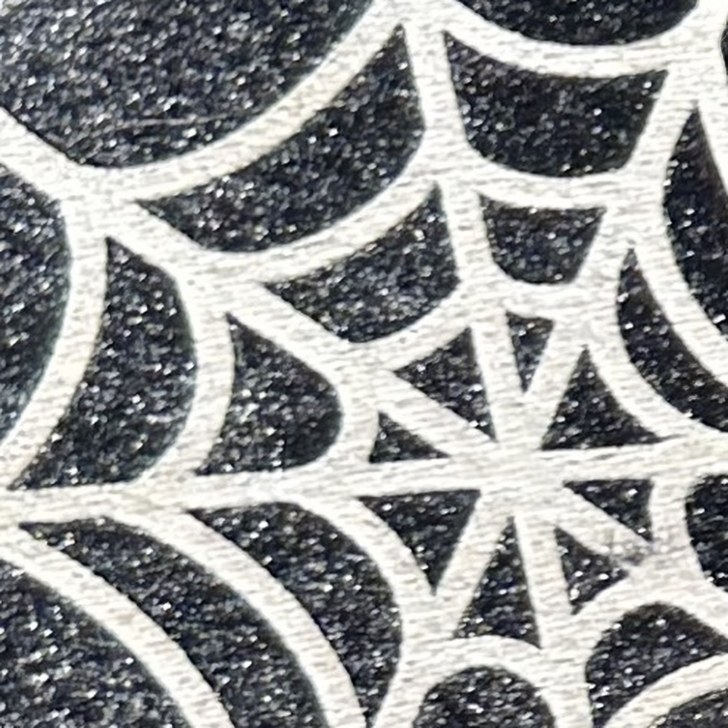 Gros plan photographique du motif toile d’araignée claire sur une oreille noire scintillante du set Halloween Mickey.