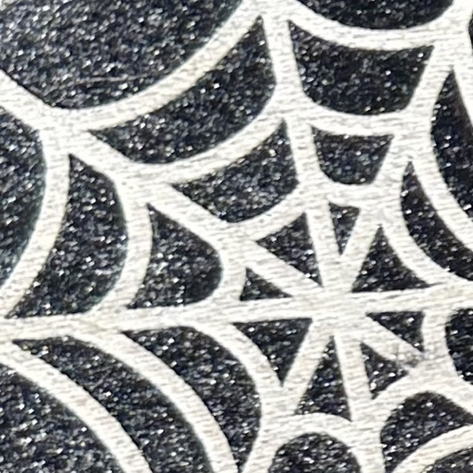 Gros plan photographique du motif toile d’araignée claire sur une oreille noire scintillante du set Halloween Mickey.