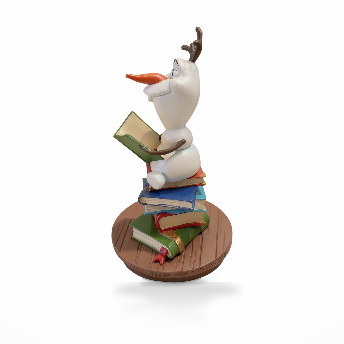 Dekorative Figur von Olaf, lesend auf einem Bücherstapel, linke Profilansicht vor weißem Hintergrund