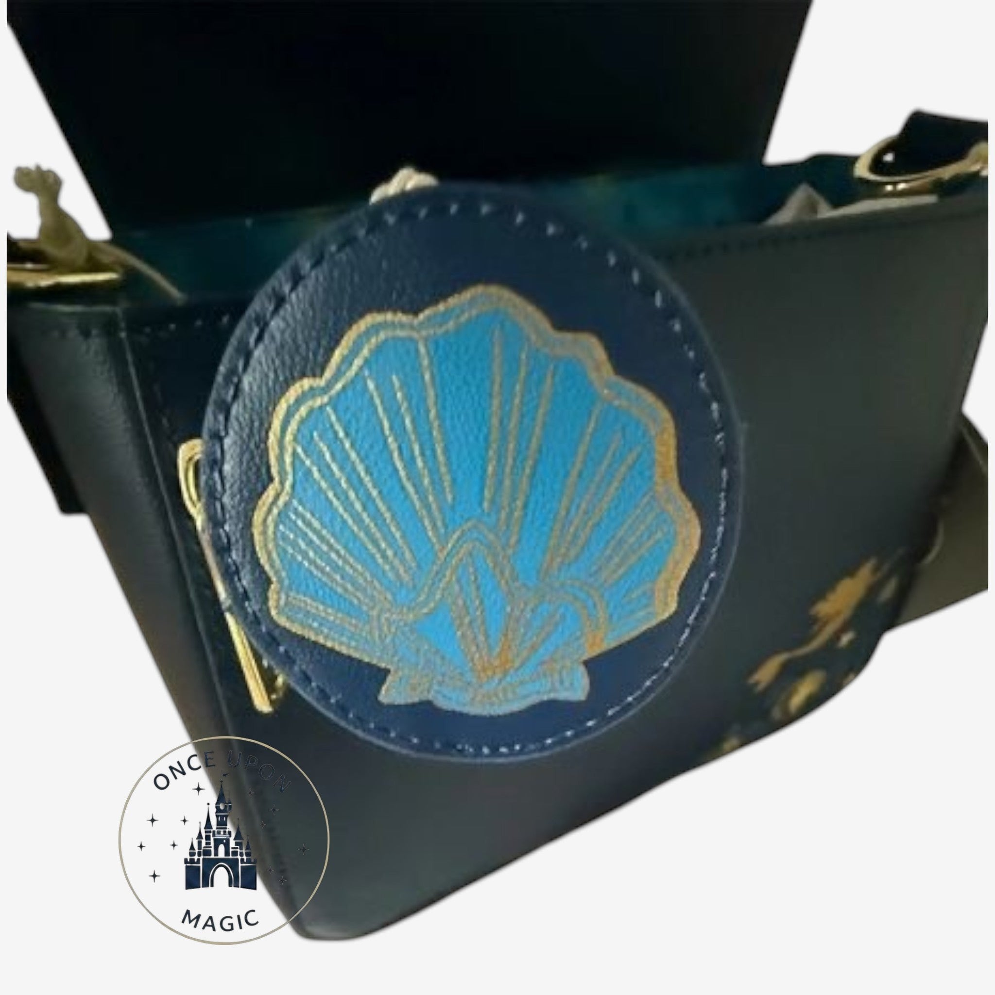 Once Upon Magic dark blue faux leather crossbody bag with a gold trimmed blue seashell applique and Ariel silhouette detail.