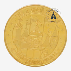 Once Upon Magic gold-toned Disneyland Paris It's A Small World commemorative coin with embossed attraction facade.