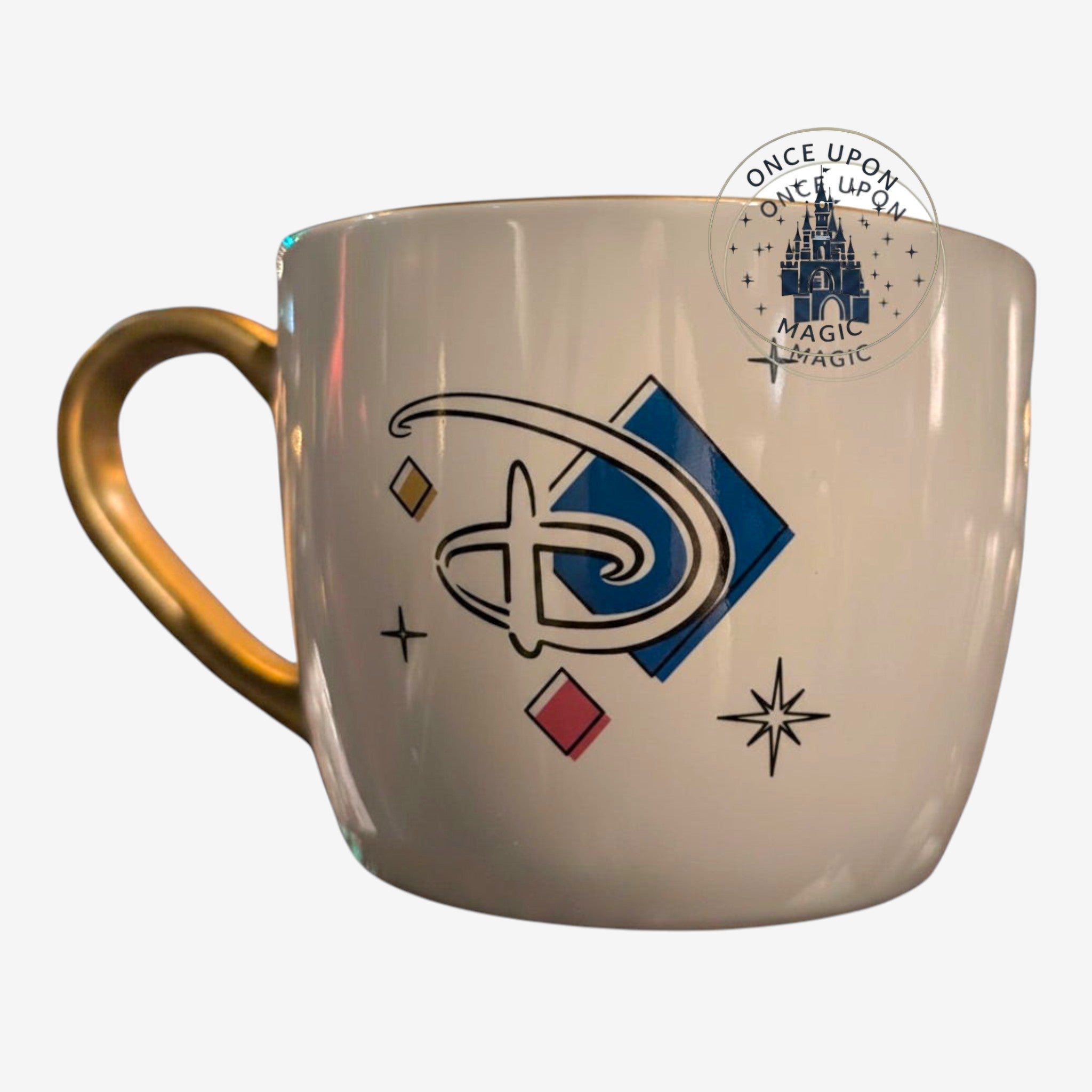 Once Upon Magic white ceramic mug with gold handle, featuring the Disneyland Paris 2024 collection logo and geometric accents.
