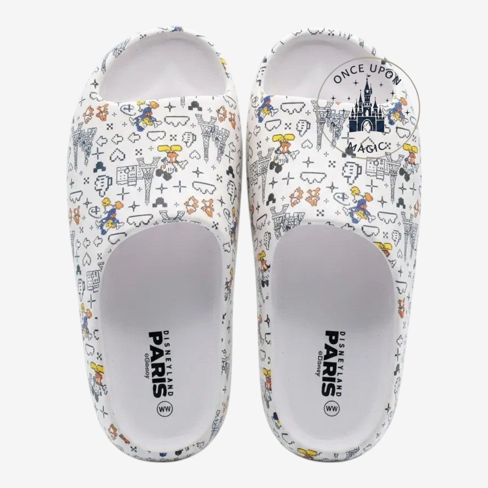 Once Upon Magic white slides with all-over pixelated Disney character and Eiffel Tower print. Slip-on design.