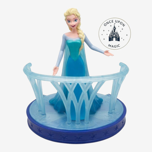 Once Upon Magic Frozen Elsa figurine in an ice-blue gown on a snowflake-themed display stand with a translucent railing.