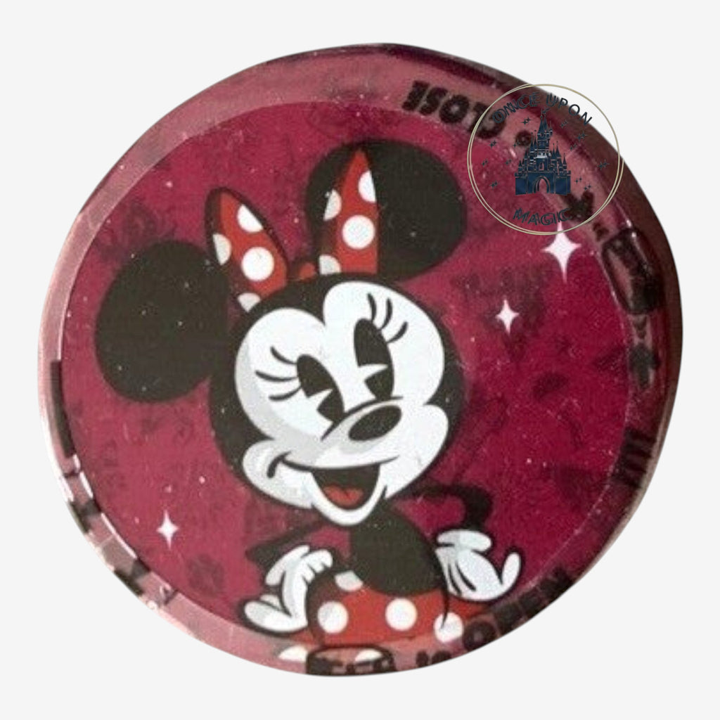 Once Upon Magic Minnie Mouse collectible pin with red polka dot bow and dress, surrounded by sparkles on a dark pink background.