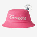 Once Upon Magic pink cotton bucket hat with white Disneyland Paris embroidery hanging on a store display rack.