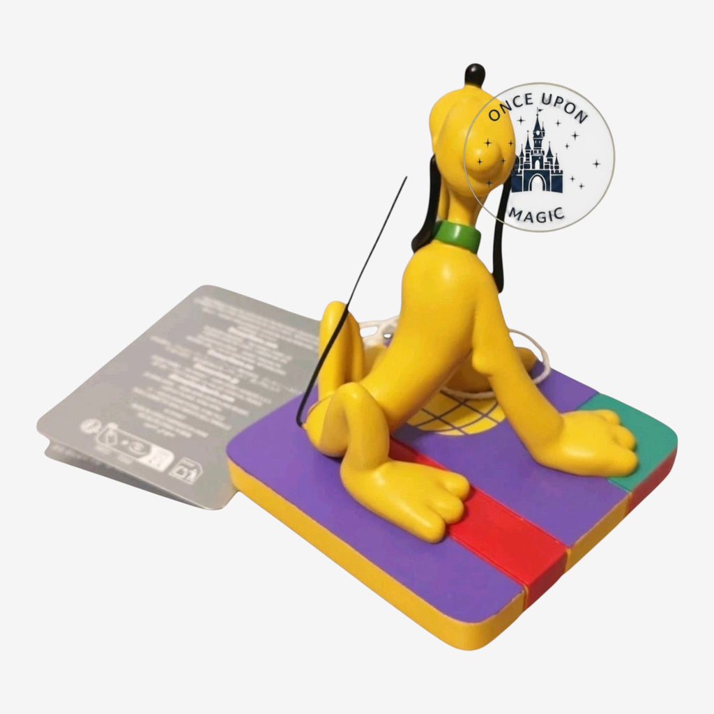 Once Upon Magic Pluto figurine sitting on a colorful square base with a green collar, rear view