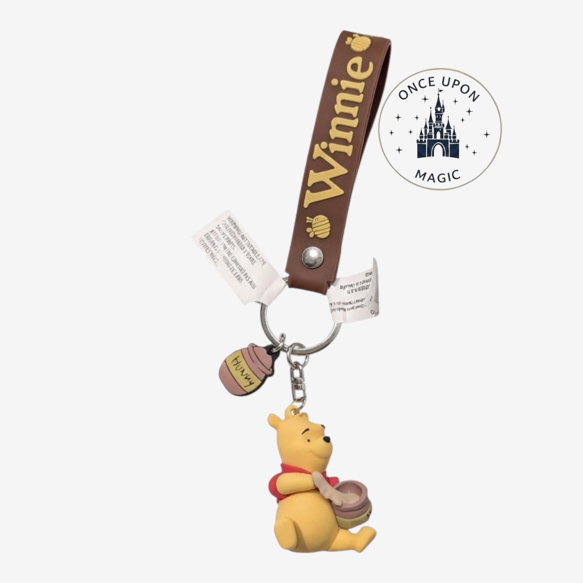 Porte-clé Once Upon Magic en silicone Winnie l’Ourson avec lanière marron, figurine et charm pot de miel.