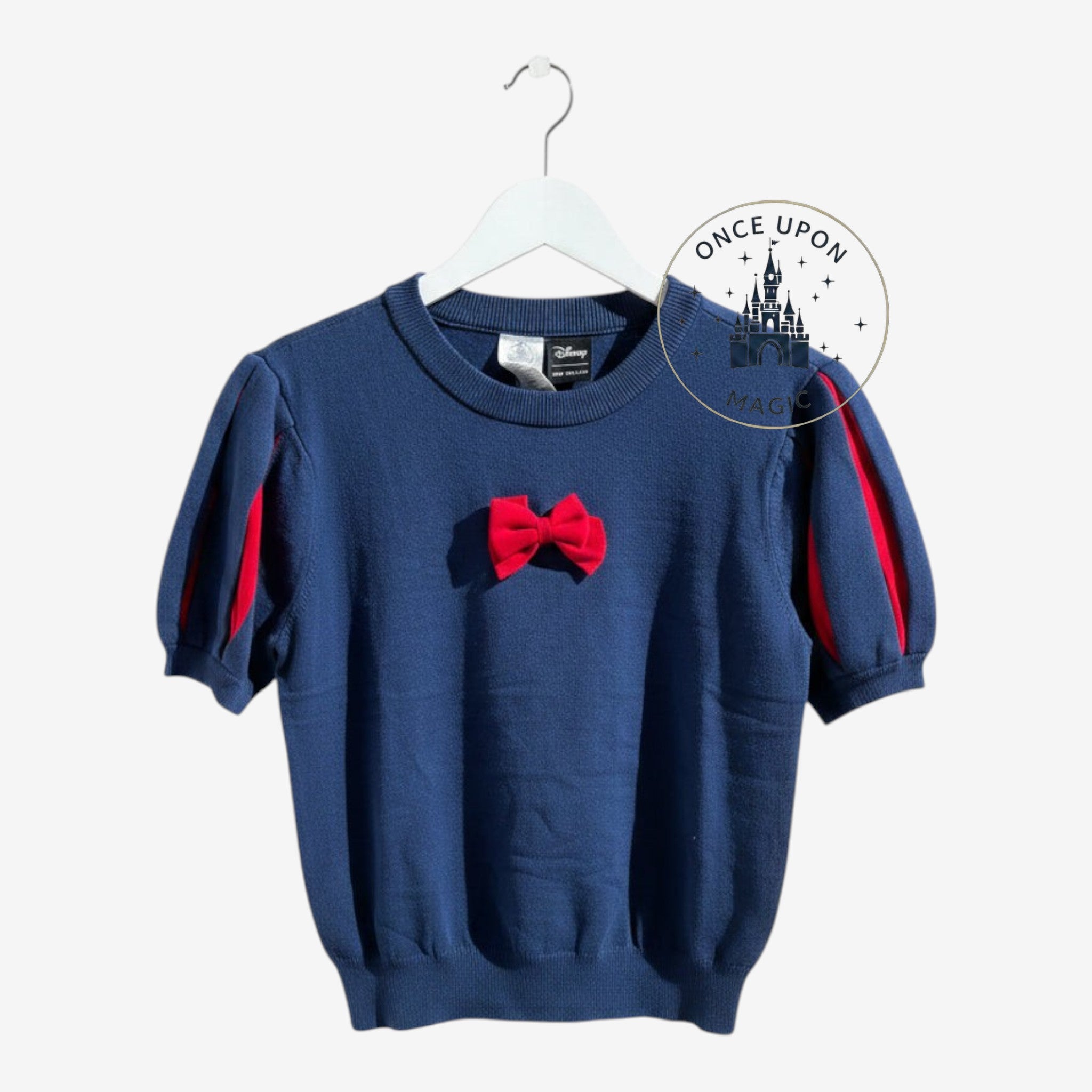 Once Upon Magic Disney Snow White navy blue knit top with puff sleeves and a red bow detail on a white hanger.