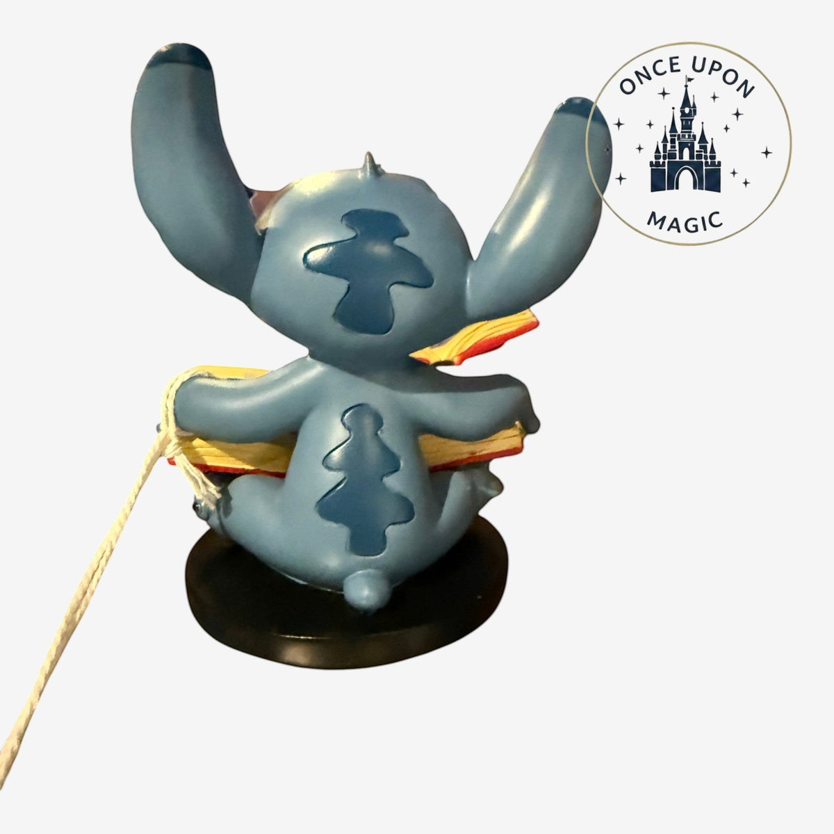 Once Upon Magic blue Stitch figurine sitting on a black base reading a book, inspired by Lilo & Stitch.