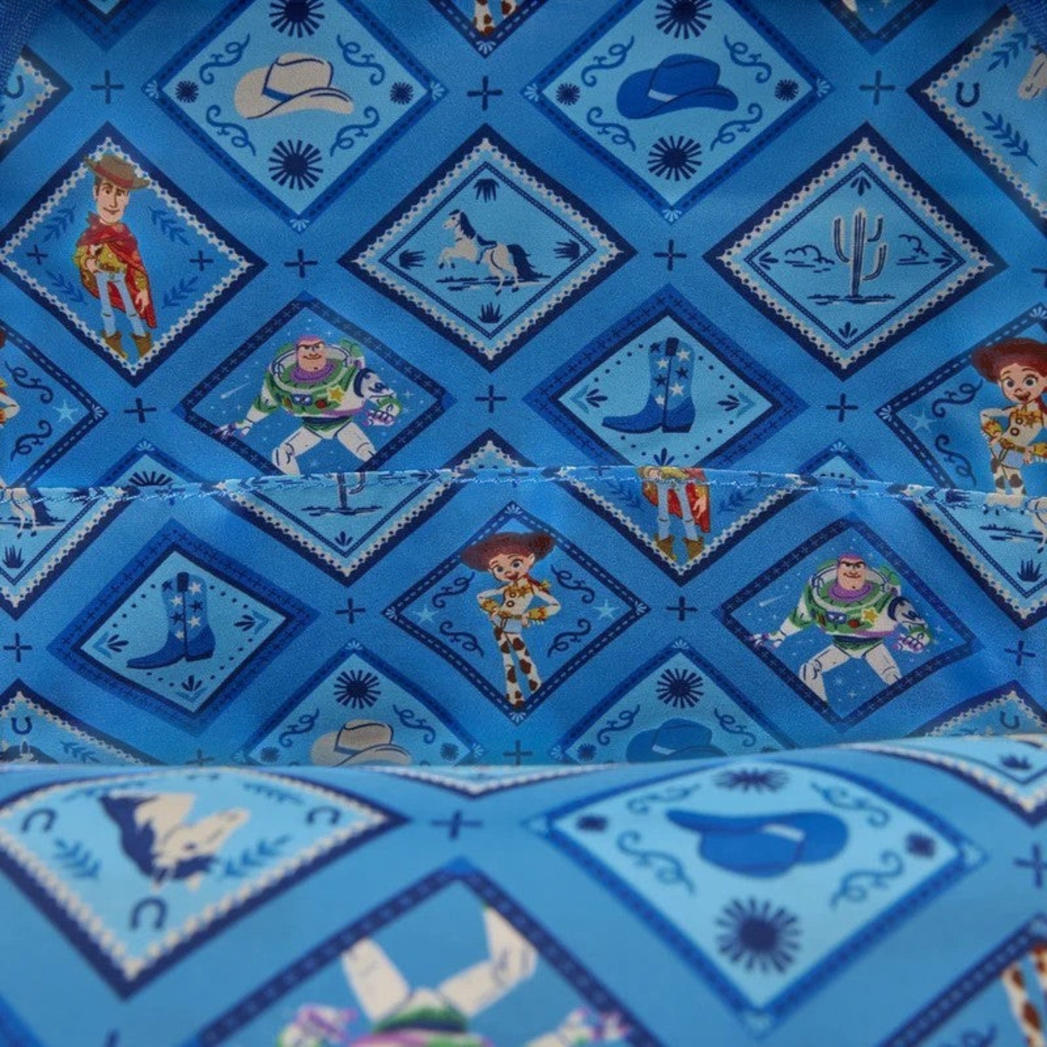 Once Upon Magic Toy Story backpack lining with Woody, Buzz, Jessie, horses, boots, and cowboy hats on blue diamond pattern.