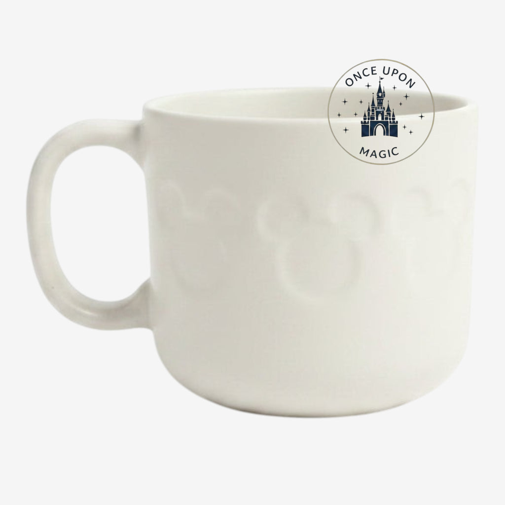 Once Upon Magic white ceramic mug from Disneyland Paris featuring a subtle embossed Mickey Mouse icon pattern.