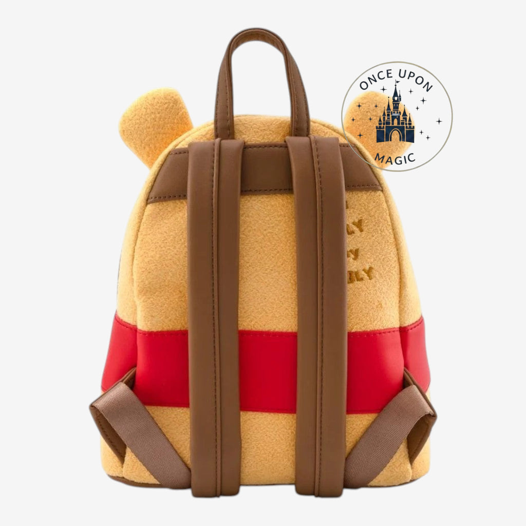 Once Upon Magic Winnie the Pooh mini backpack in fuzzy yellow with red band and brown straps. Features Pooh ears and honey pot design.