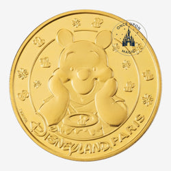 Once Upon Magic gold collector coin featuring Winnie the Pooh with a honey pot and Disneyland Paris branding.