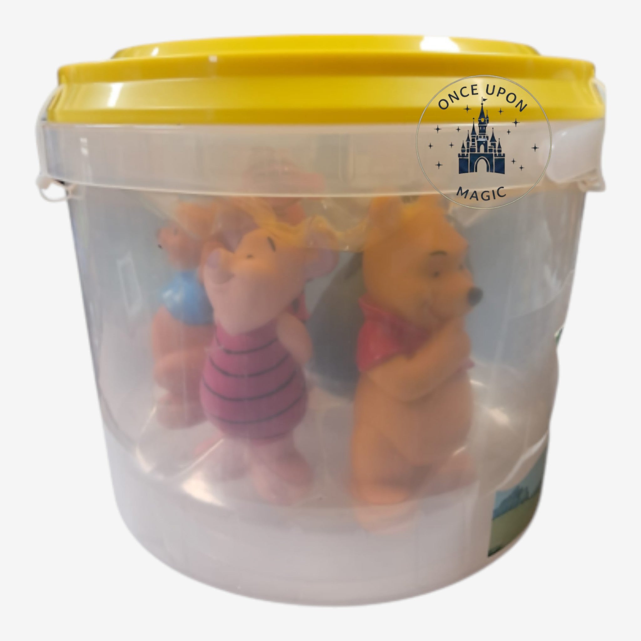 Once Upon Magic Winnie the Pooh character figurine set inside a clear plastic storage bucket with a yellow lid.