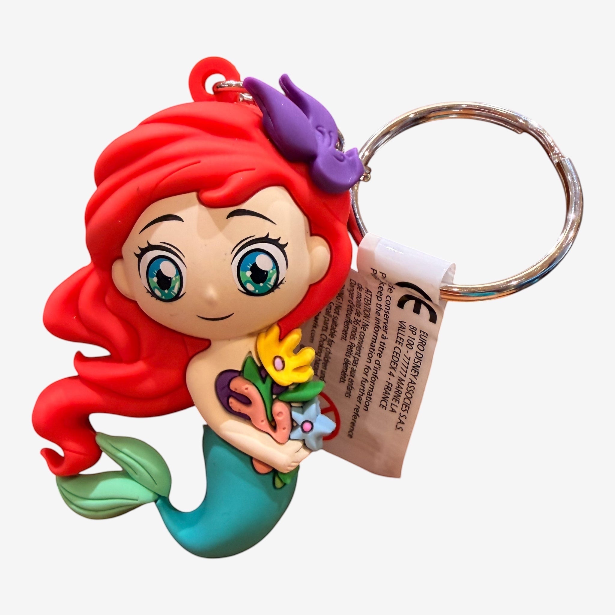 Once Upon Magic Ariel keychain, a 3D soft PVC charm featuring the Little Mermaid with red hair, turquoise tail, and holding flowers. Includes a silver clasp.