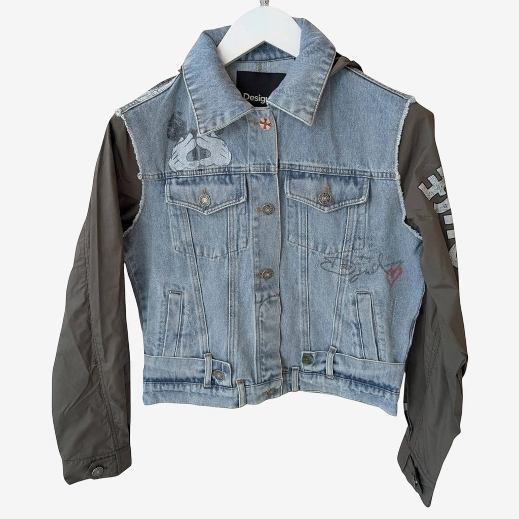 Once Upon Magic x Desigual x Disneyland Paris denim jacket with contrasting olive green sleeves, featuring graphic prints and embroidery.