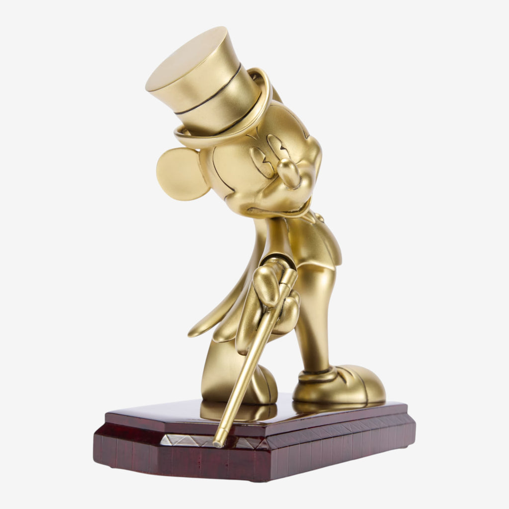 Figurine dorée de Mickey Mouse en costume hollywoodien, portant un haut-de-forme et une canne, sur un socle effet bois verni. Réplique officielle Disneyland Paris.