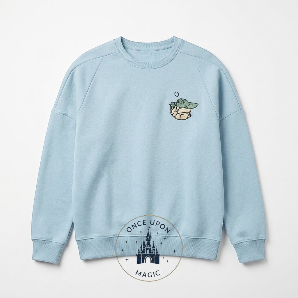 Once Upon Magic light blue crewneck sweatshirt with embroidered Grogu from The Mandalorian on the left chest.
