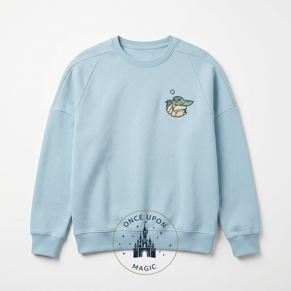 Once Upon Magic light blue crewneck sweatshirt with embroidered Grogu (The Child) from The Mandalorian. Soft fabric, relaxed fit.
