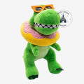 Peluche dinosaure vert Once Upon Magic avec lunettes de soleil orange et tour de cou beigne rose et jaune.