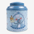 Once Upon Magic blue tin tea box featuring Remy from Ratatouille holding a stack of cheese and cake, with Eiffel Tower background.
