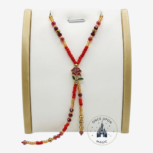 Once Upon Magic beaded lariat necklace with red and gold beads, featuring a rose charm and deep red crystal accents. Adjustable design.