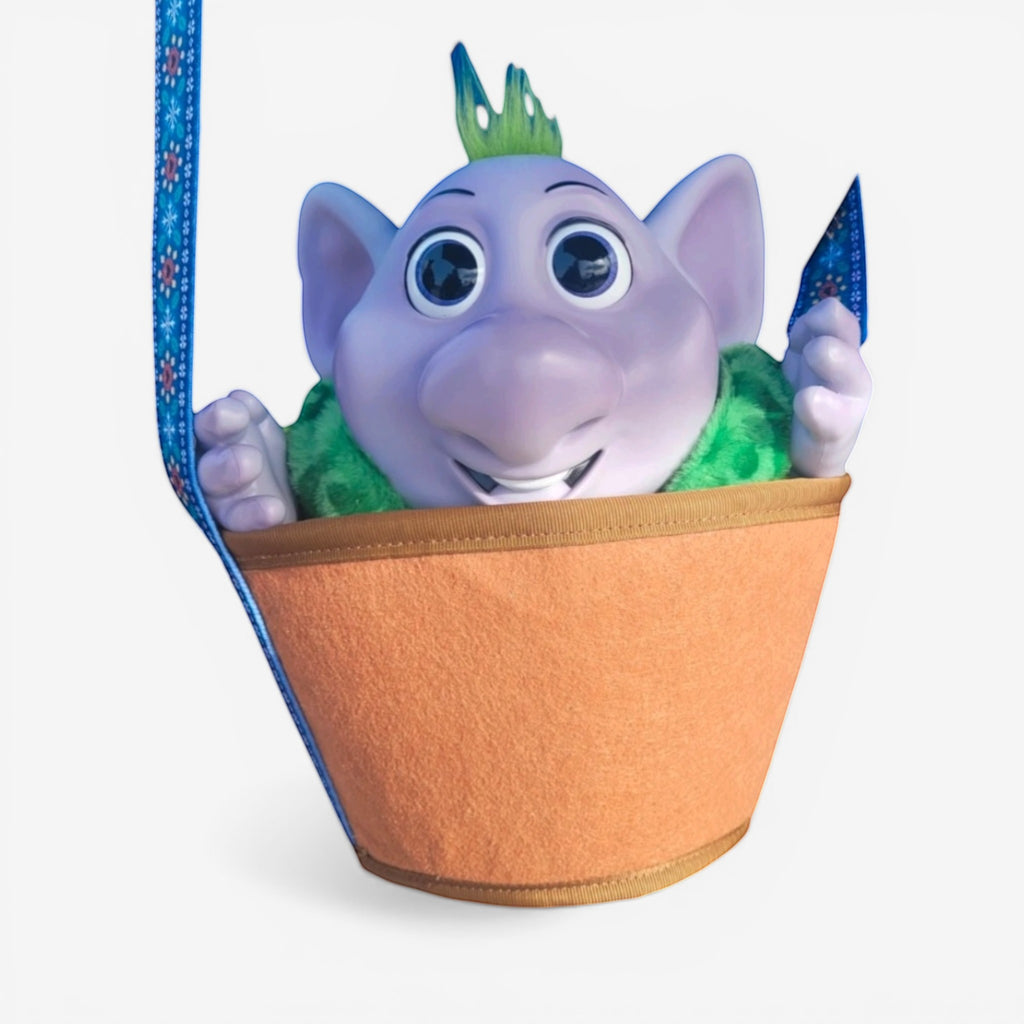 Once Upon Magic Runa interactive plush toy from Frozen, purple troll with green hair, wearing a green fuzzy vest, in an orange bucket.