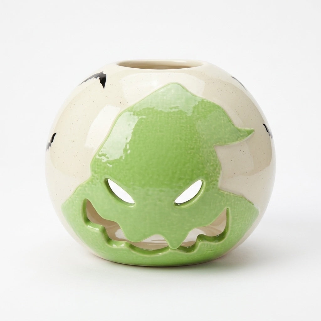 Once Upon Magic spooky ceramic lantern with a grinning jack-o'-lantern face, glowing eyes, and bat accents. Cream and green glaze.