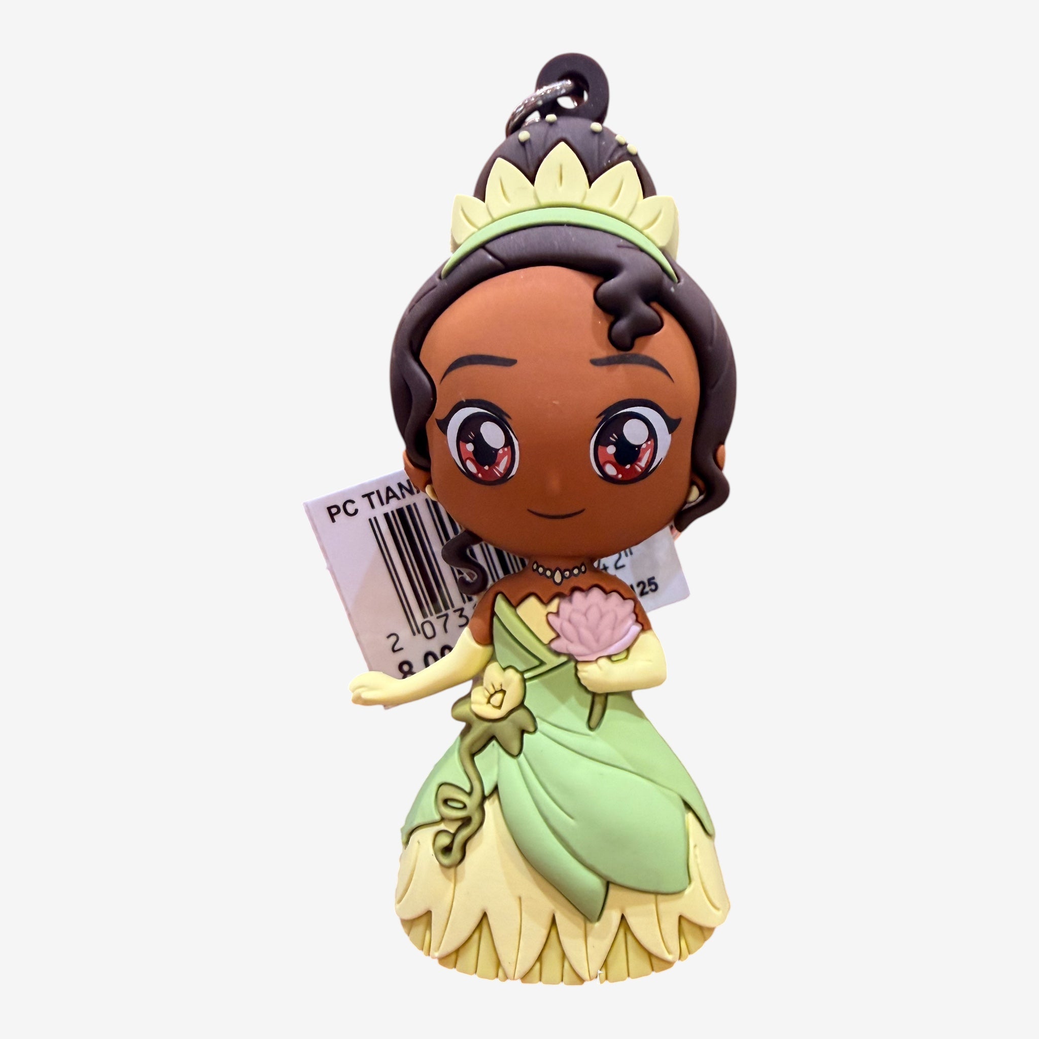 Once Upon Magic Tiana keychain from The Princess and the Frog, wearing a green dress and holding a pink lotus flower. Made of soft PVC.