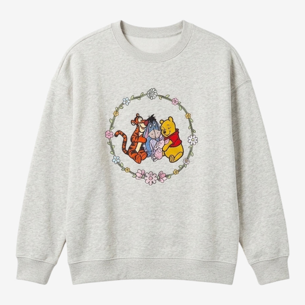 Once Upon Magic light grey crewneck sweatshirt with Winnie the Pooh, Tigger, Eeyore, and Piglet graphic in a floral wreath.